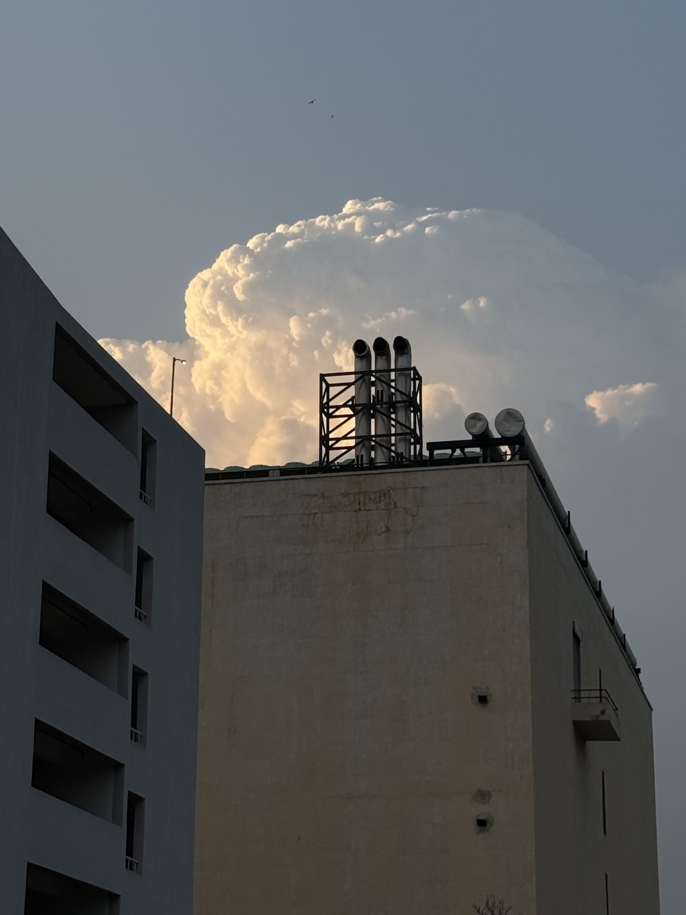 Tall cloud over city rooftops at blue hour