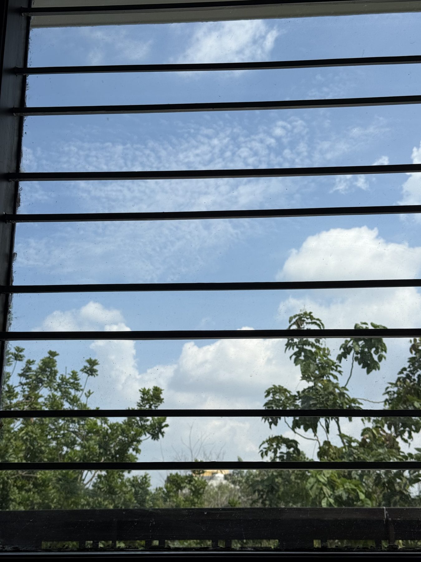 Blue sky and clouds seen through window security bars