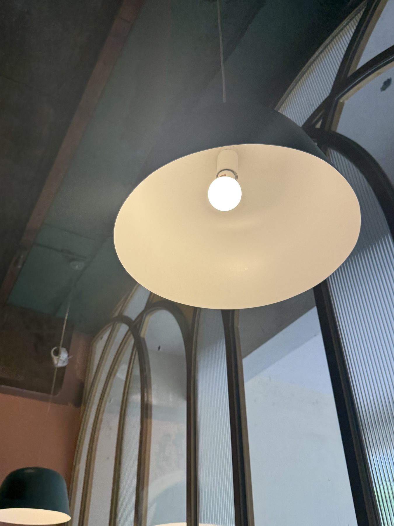 Modern pendant lamp glowing against dark arched glass