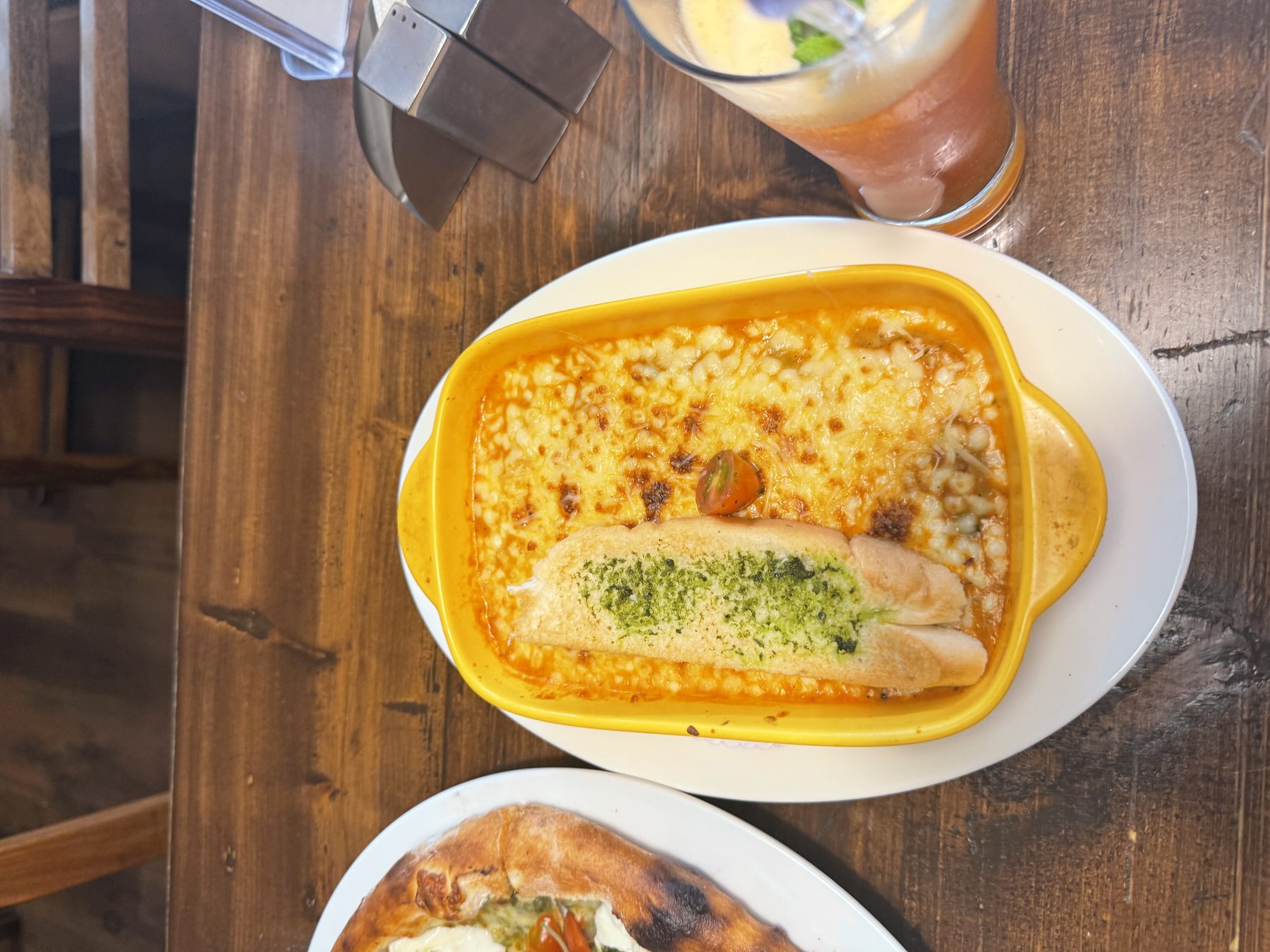 Bubbling baked cheesy pasta beside a tall layered iced drink