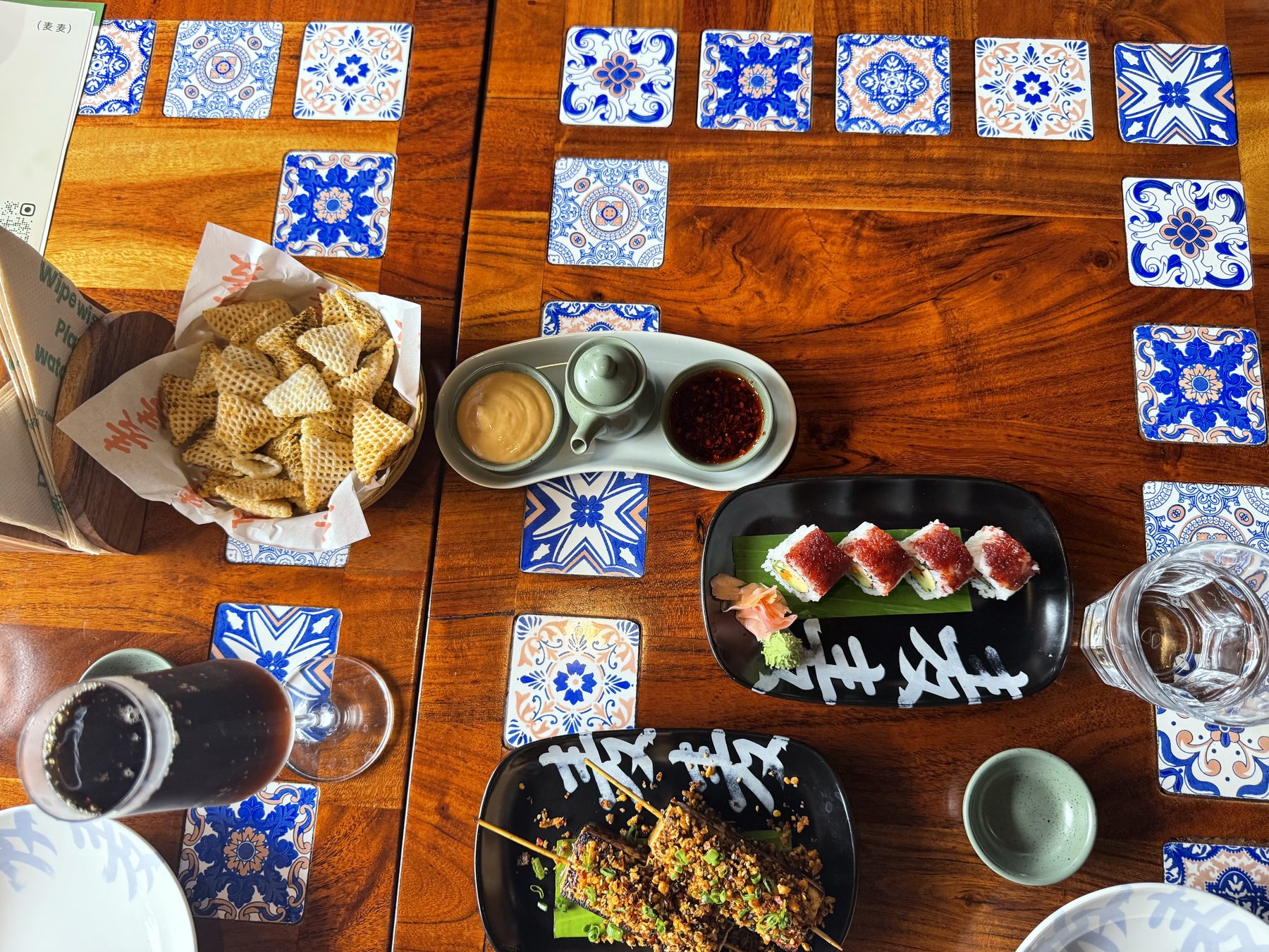 Shared table of Asian appetizers, sushi, skewers, and drinks