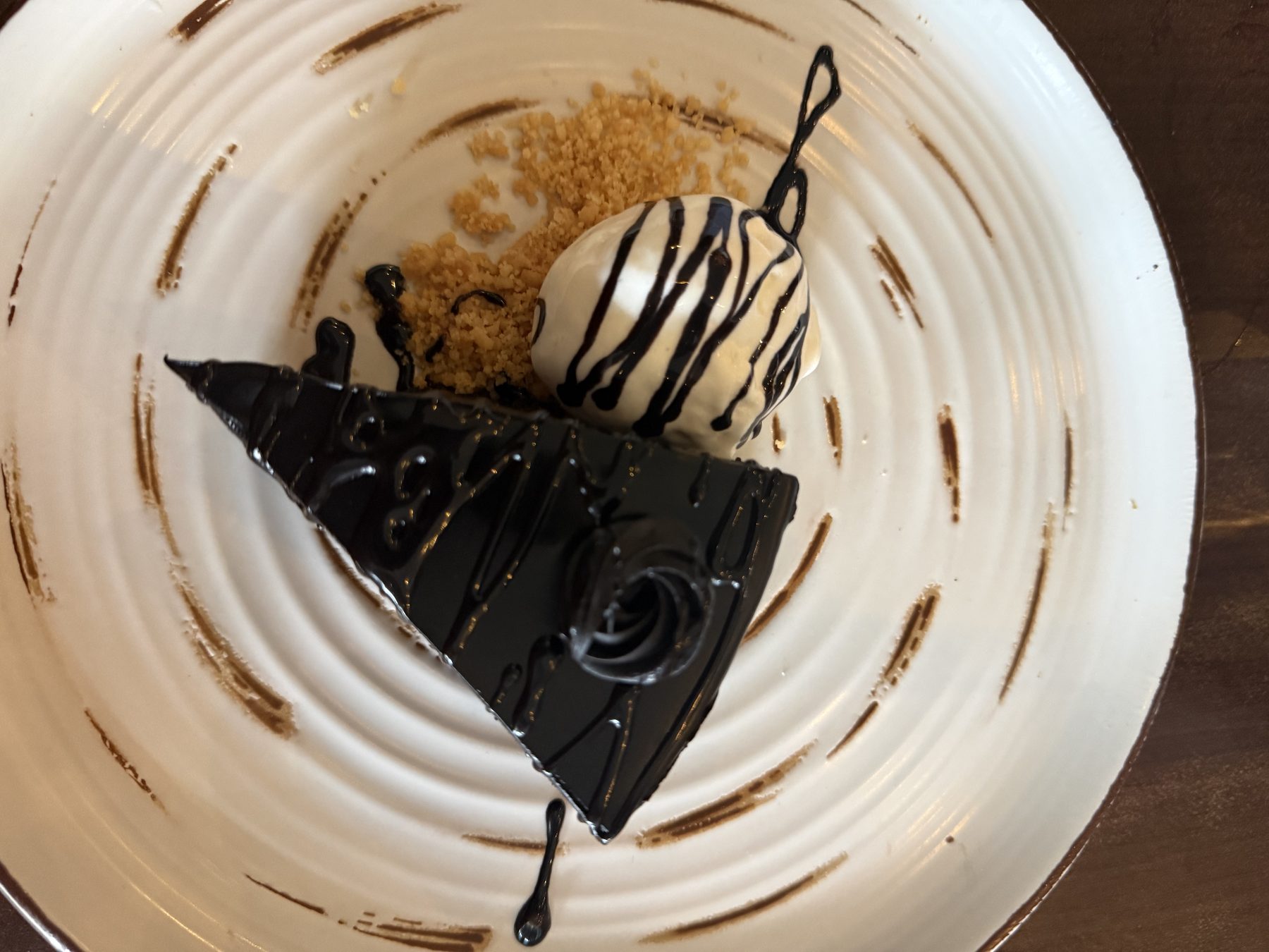Glossy chocolate cake with vanilla ice cream and cookie crumbs