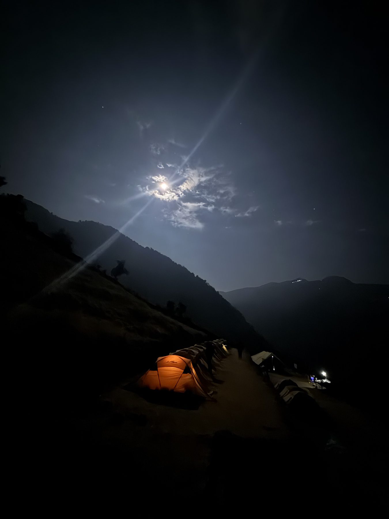 Moonlit mountain camp with a warmly glowing tent