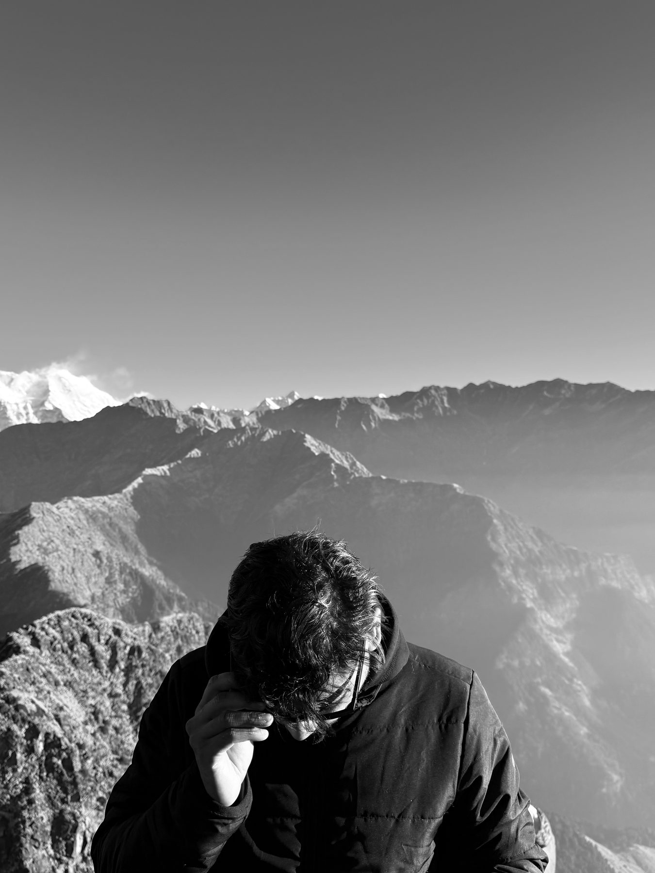 Black-and-white portrait before a vast snow-dusted mountain range
